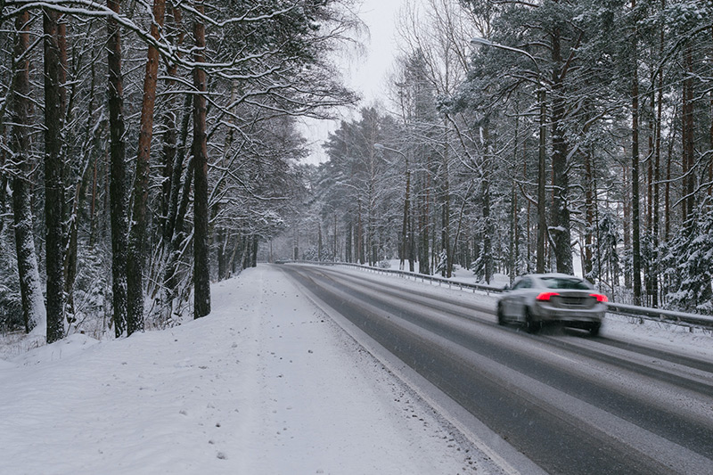 Car driving through a snowy forest