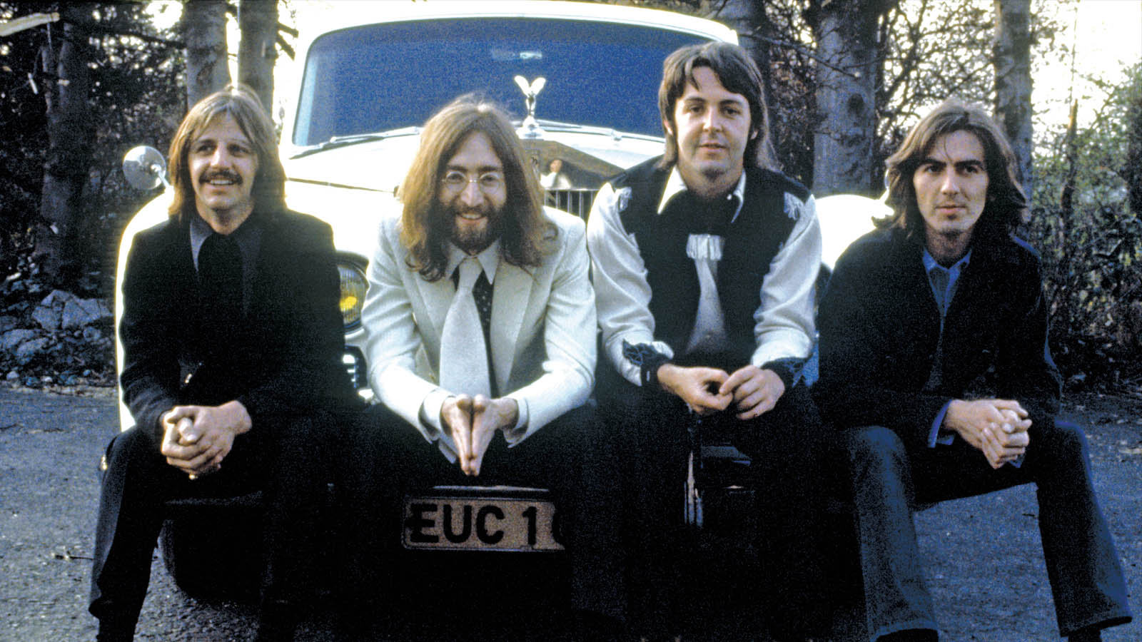 The Beatles sitting on the front of a car