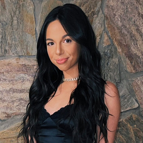 Lindsay smiling in front of a stone wall