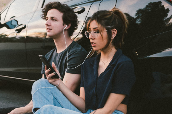 Man and Women listen to music on phone headphones
