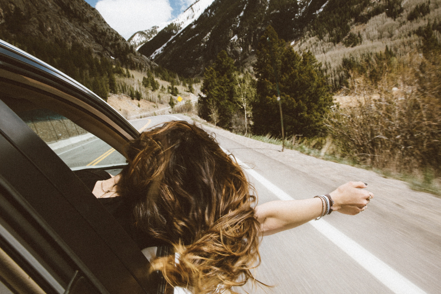 Car Driving around mountains with women sticking head out window
