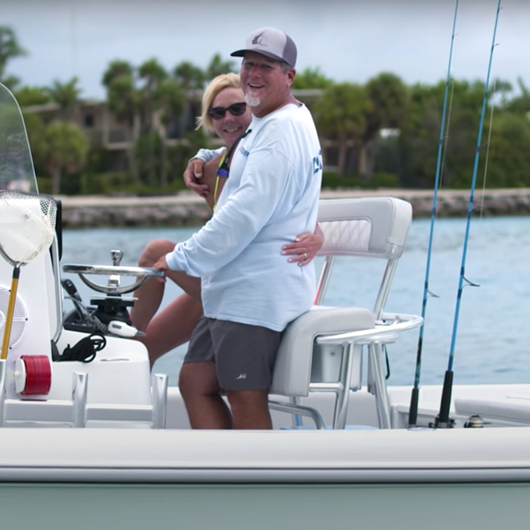 Greg smiles on a boat, hugging a woman