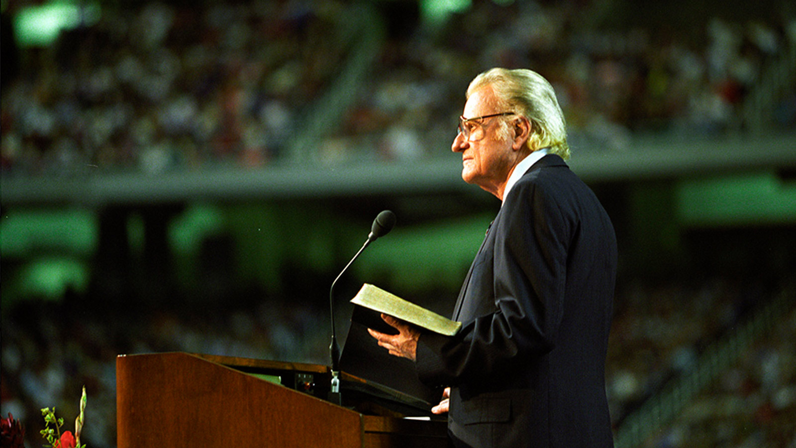 Billy Graham standing at a podium in a stadium